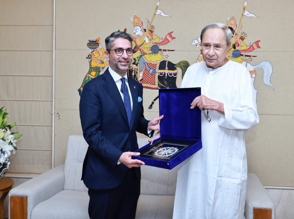 Abhinav Bindra in a suit holding a memento beside Naveen Patnaik