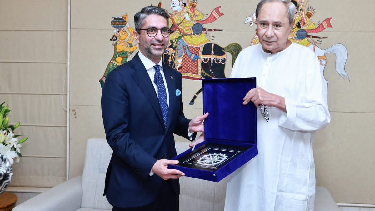 Abhinav Bindra in a suit holding a memento beside Naveen Patnaik