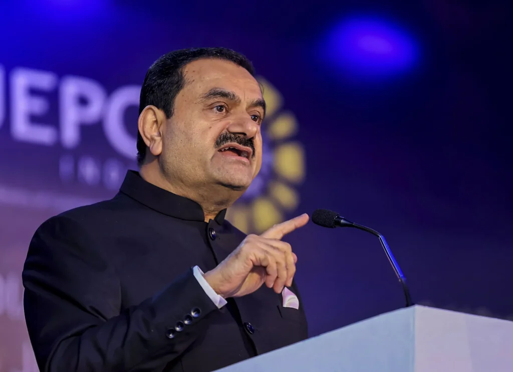 Gautam Adani speaking at a podium and gesturing with his hand