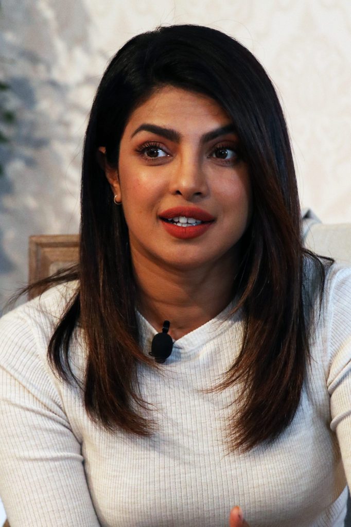 Priyanka Chopra Jonas in a white sweater speaking at the Global Education and Skills Forum in Dubai