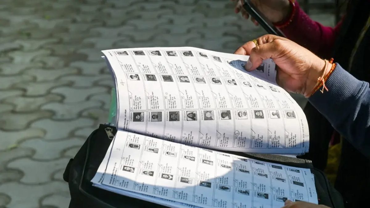 A person turning the pages of a printed electoral roll with voters photographs