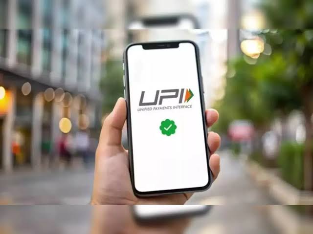 A hand holding a smartphone showing the UPI logo