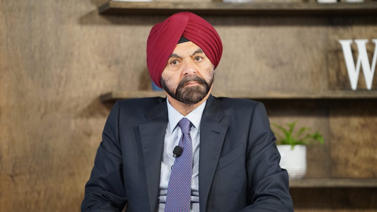 Ajay Banga in a red turban and dark suit, seated and smiling