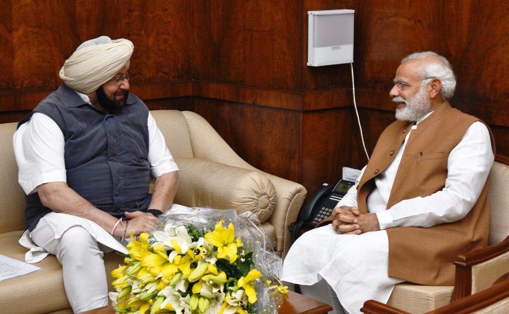 Amarinder Singh in a turban and waistcoat seated in conversation with Prime Minister Narendra Modi