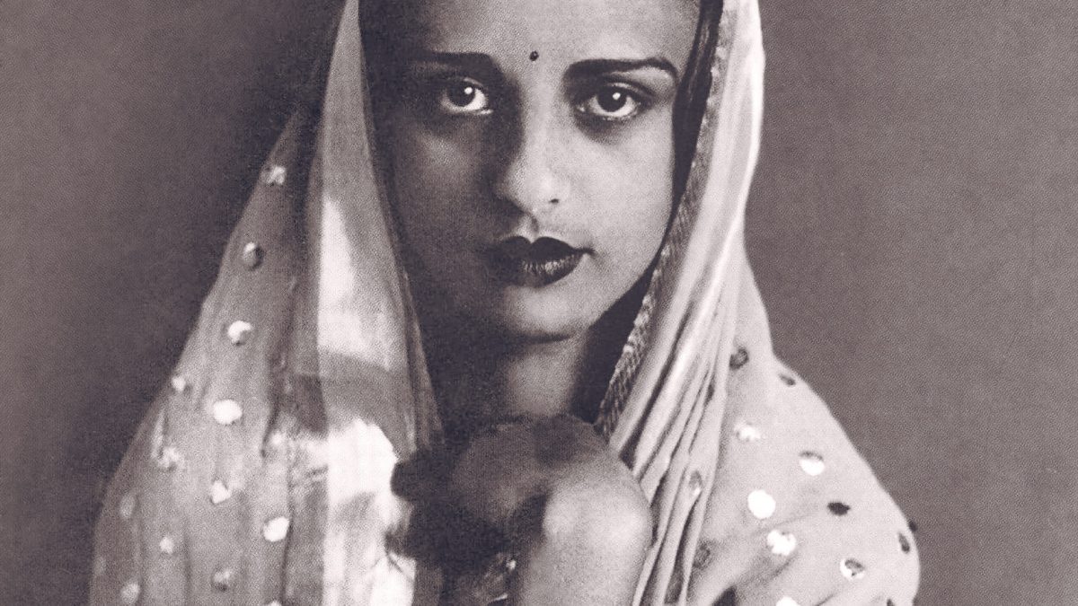 A black-and-white portrait of Amrita Sher-Gil in a sari, looking at the camera