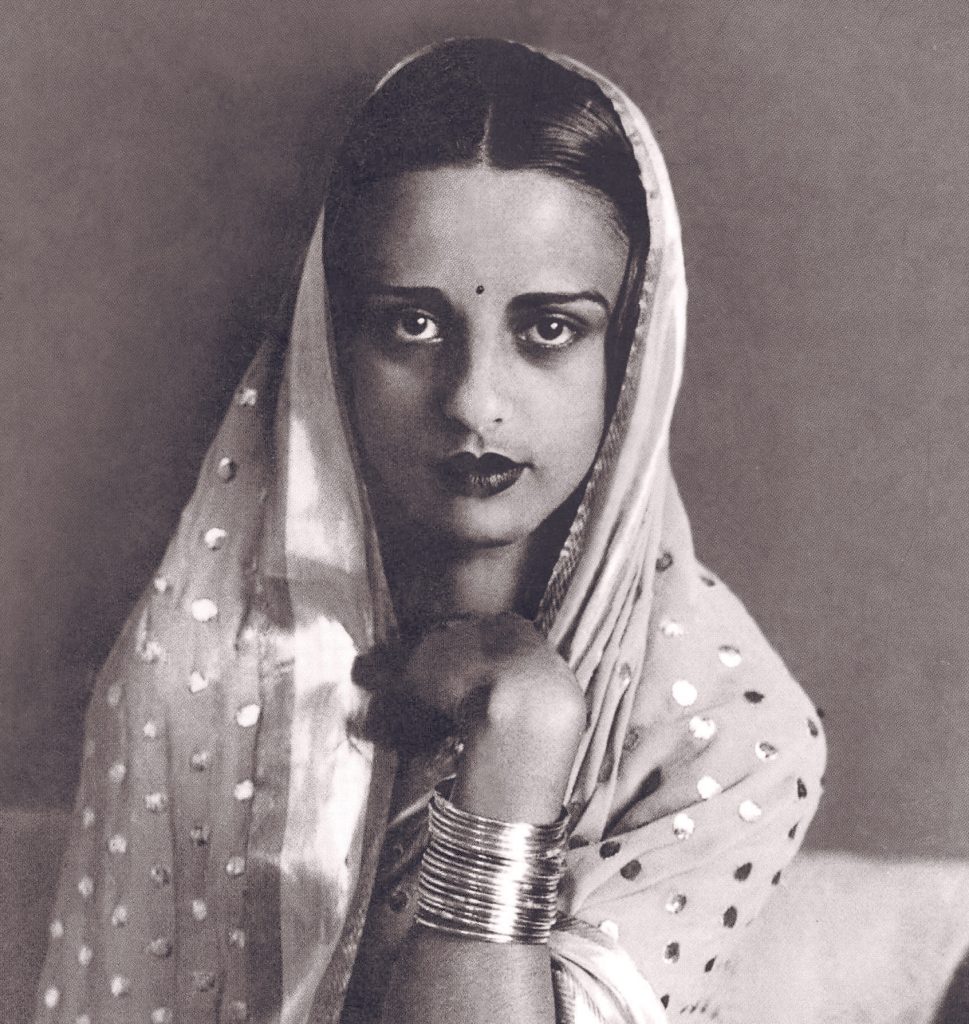 A black-and-white portrait of Amrita Sher-Gil in a sari, looking at the camera