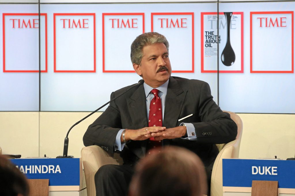 Anand Mahindra in a dark suit and red tie seated on a panel at the World Economic Forum