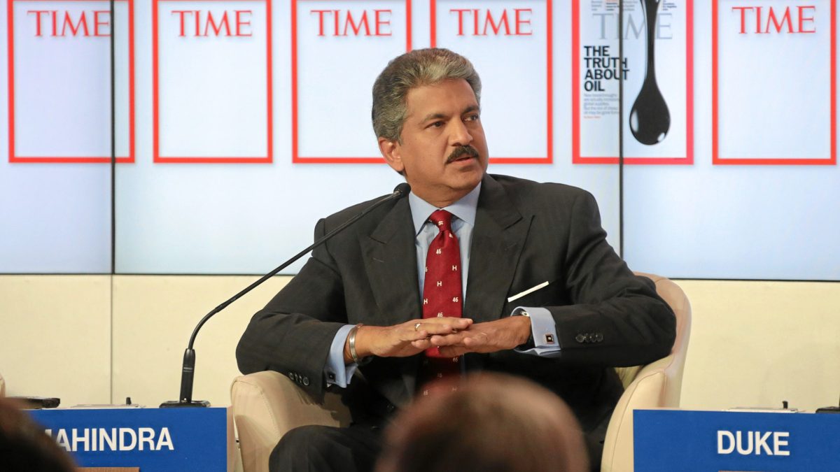 Anand Mahindra in a dark suit and red tie seated on a panel at the World Economic Forum