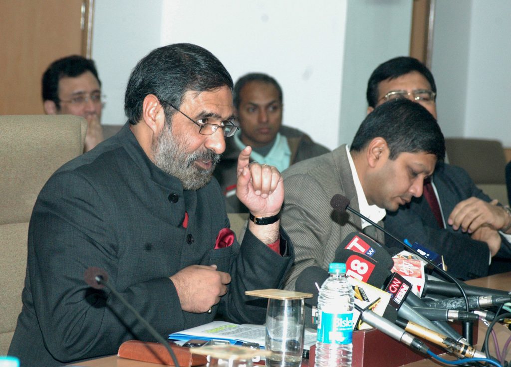 Anand Sharma in a dark bandhgala speaking at press microphones