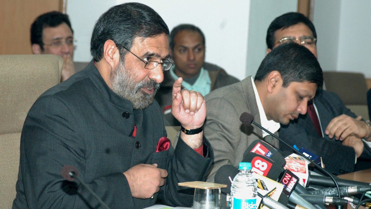 Anand Sharma in a dark bandhgala speaking at press microphones