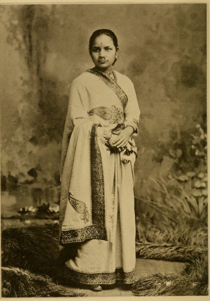 Sepia studio photograph of Anandibai Joshi standing in a sari and shawl