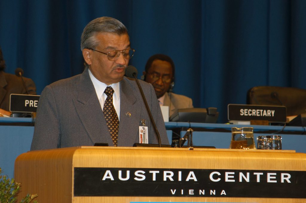Anil Kakodkar in a grey suit speaking at a lectern at the Austria Center in Vienna