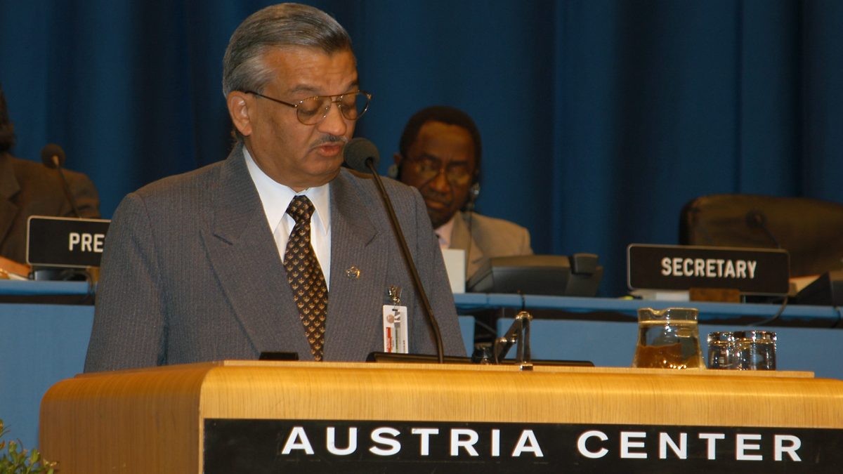 Anil Kakodkar in a grey suit speaking at a lectern at the Austria Center in Vienna
