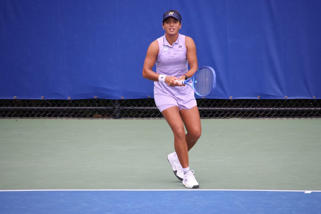 Ankita Raina in a lilac tennis dress and cap, holding her racket on court
