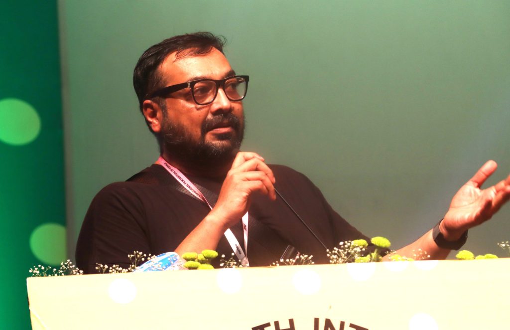 Anurag Kashyap with a beard and glasses, in a dark T-shirt, speaking into a microphone