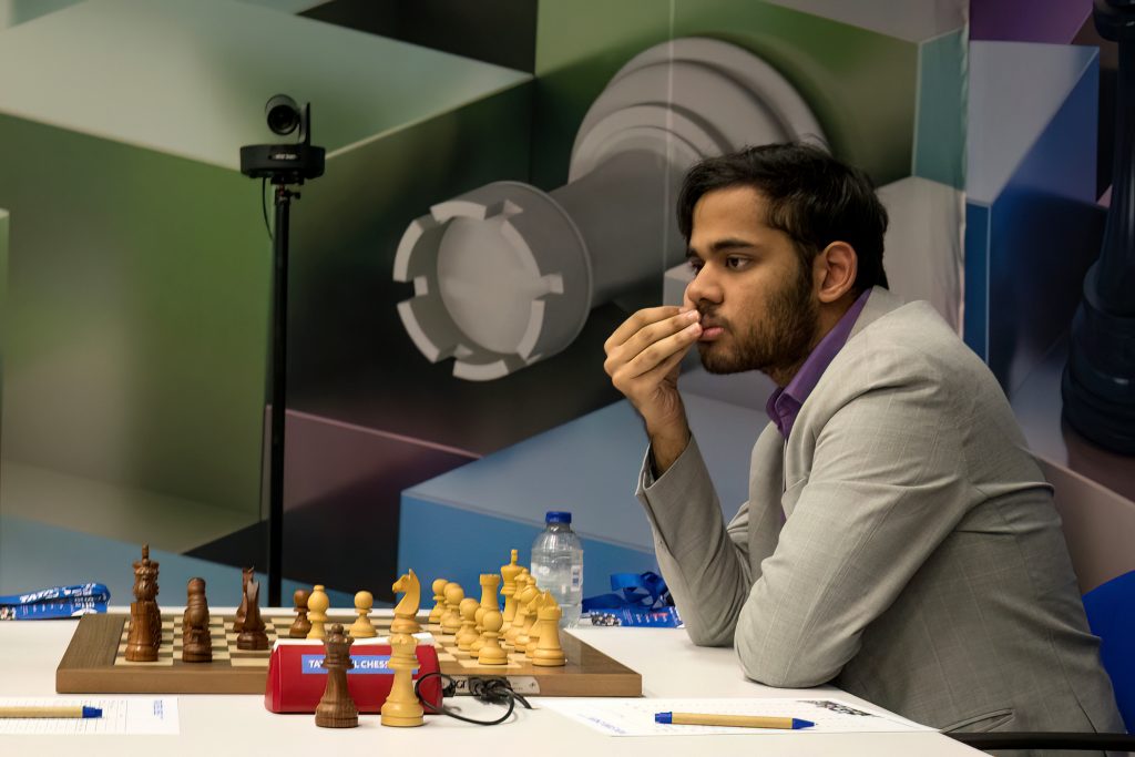 Arjun Erigaisi in a grey jacket thinking at a chessboard with his hand to his mouth