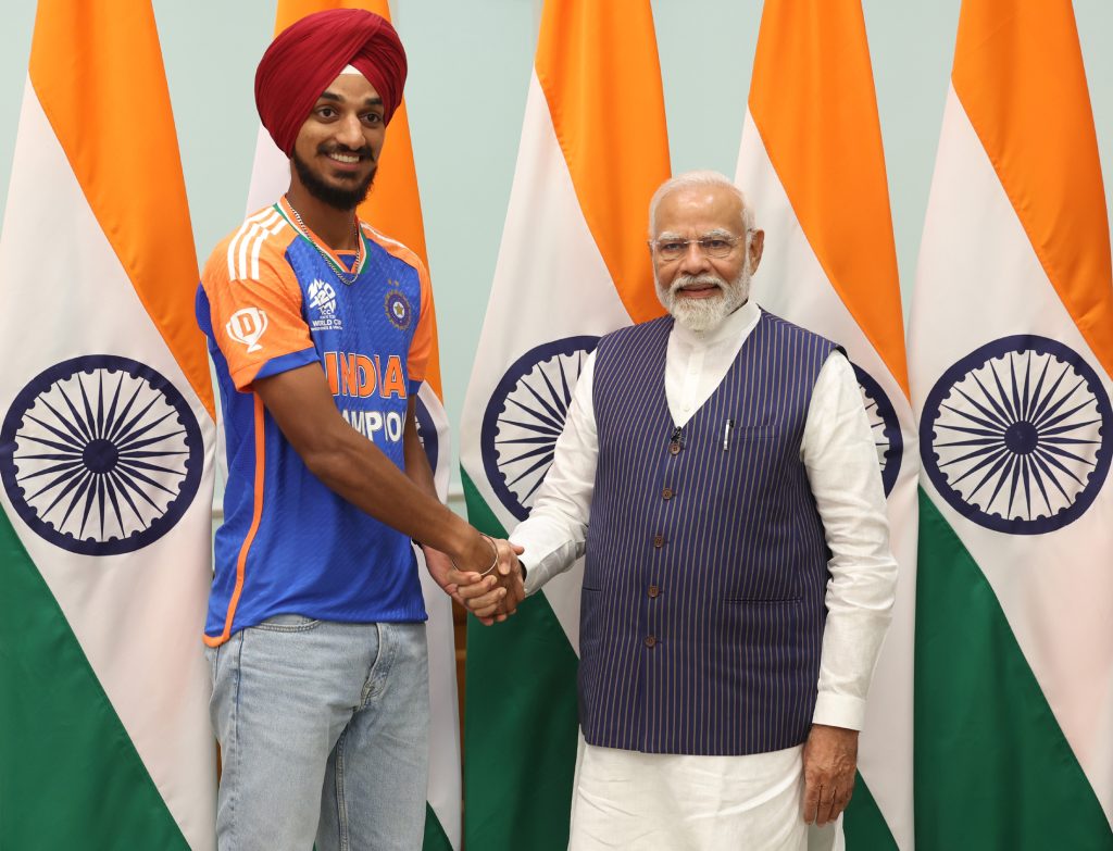 Arshdeep Singh in a maroon turban and India jersey shaking hands with Prime Minister Narendra Modi