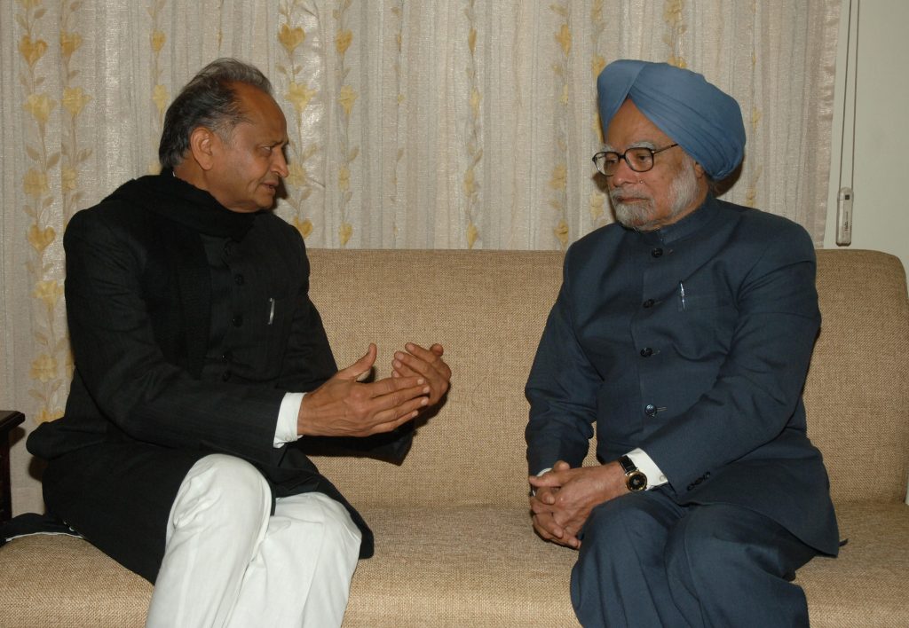Ashok Gehlot in a dark bandhgala seated in conversation with Prime Minister Manmohan Singh