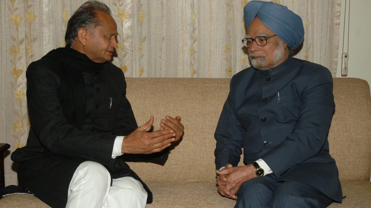 Ashok Gehlot in a dark bandhgala seated in conversation with Prime Minister Manmohan Singh
