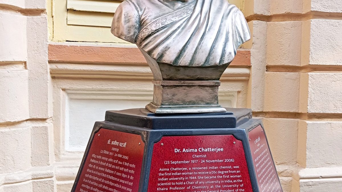 A bronze bust of Asima Chatterjee on a red pedestal