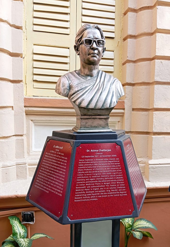 A bronze bust of Asima Chatterjee on a red pedestal