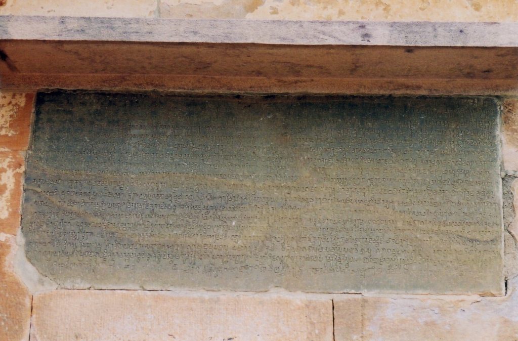 A stone slab covered with lines of old Kannada script set in the wall of the Meguti temple at Aihole