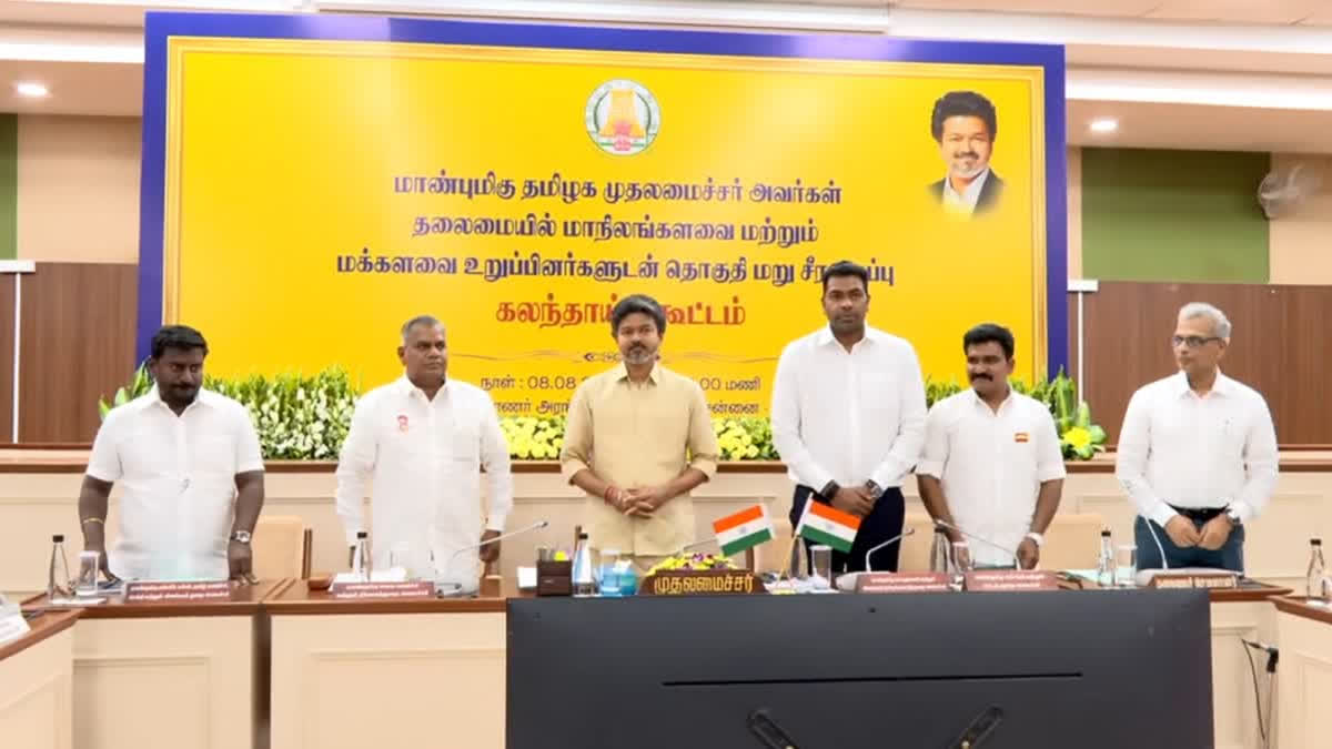 Officials standing at a meeting in Chennai under a Tamil banner on constituency delimitation