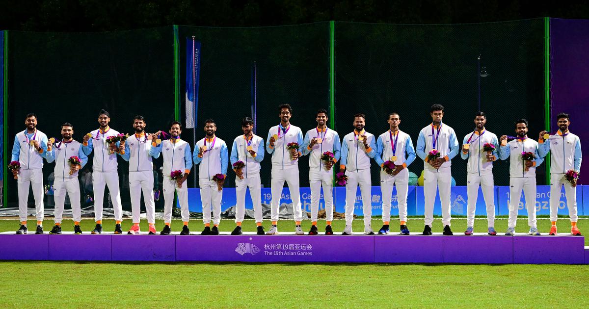 Members of the Indian men's cricket team holding gold medals on a podium at the Asian Games
