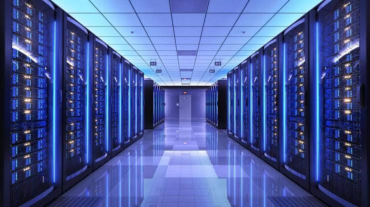 A long aisle of server racks lit in blue inside a data centre