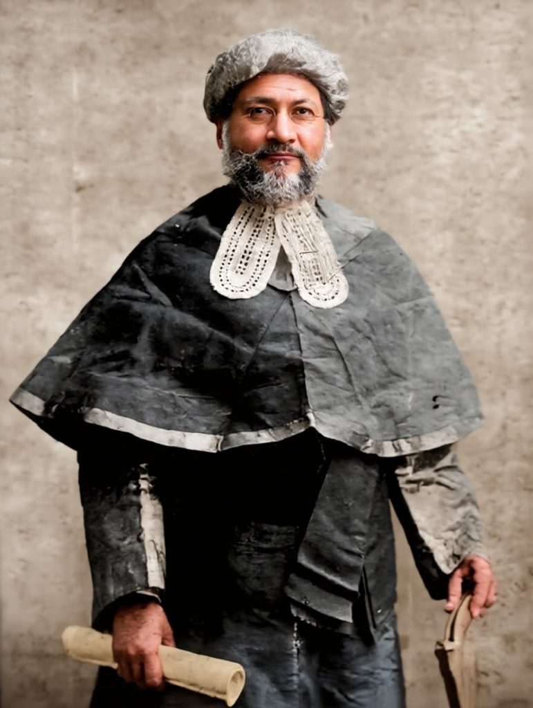 Colourised portrait of Badruddin Tyabji in a judge's wig and robes, holding a scroll