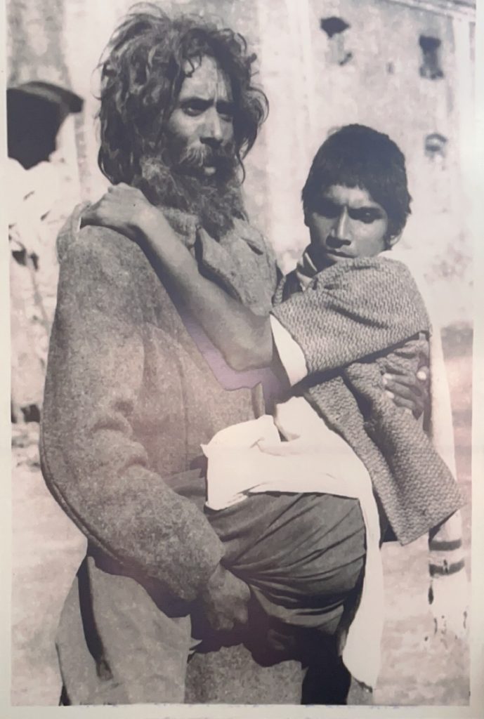 Bhagat Puran Singh, bearded and in rough clothes, carrying a disabled young man in his arms