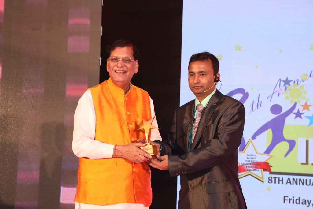 Bindeshwar Pathak in an orange waistcoat receiving an award on stage