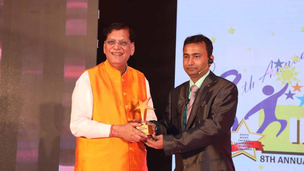 Bindeshwar Pathak in an orange waistcoat receiving an award on stage