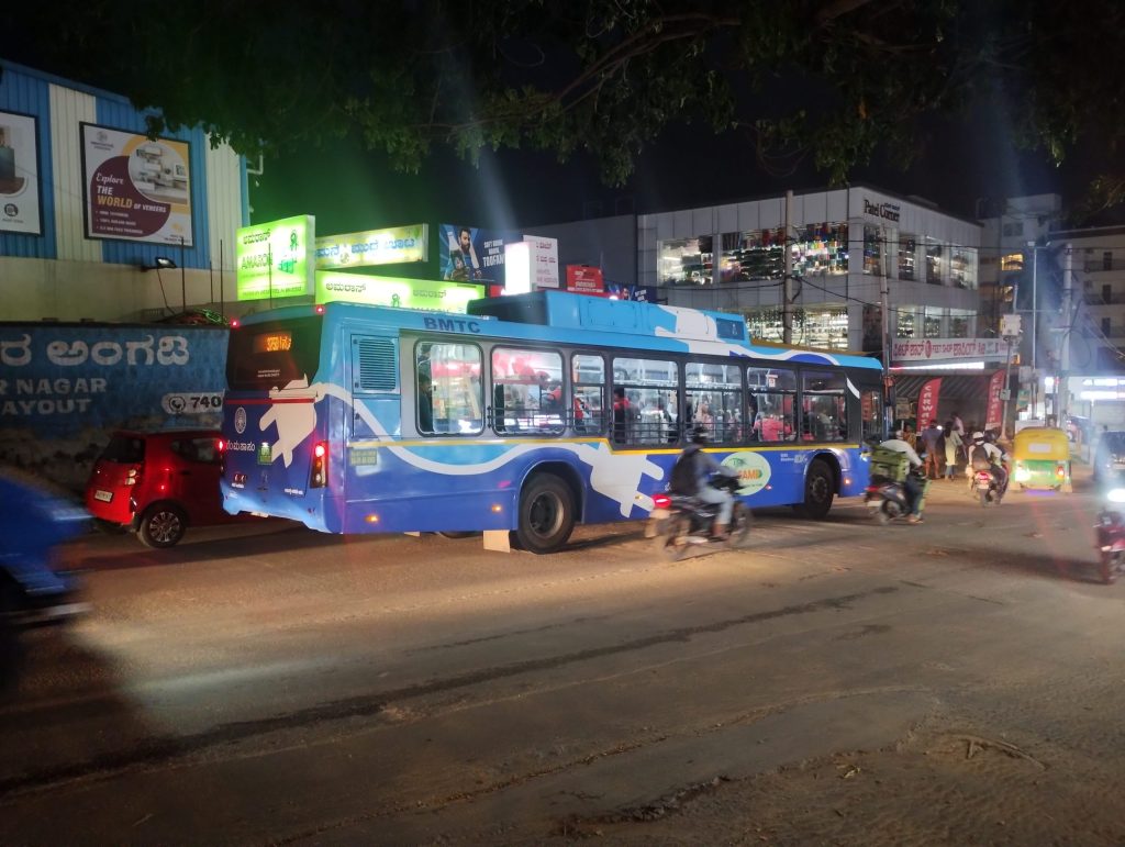 A blue BMTC city bus on a street in Bengaluru at night