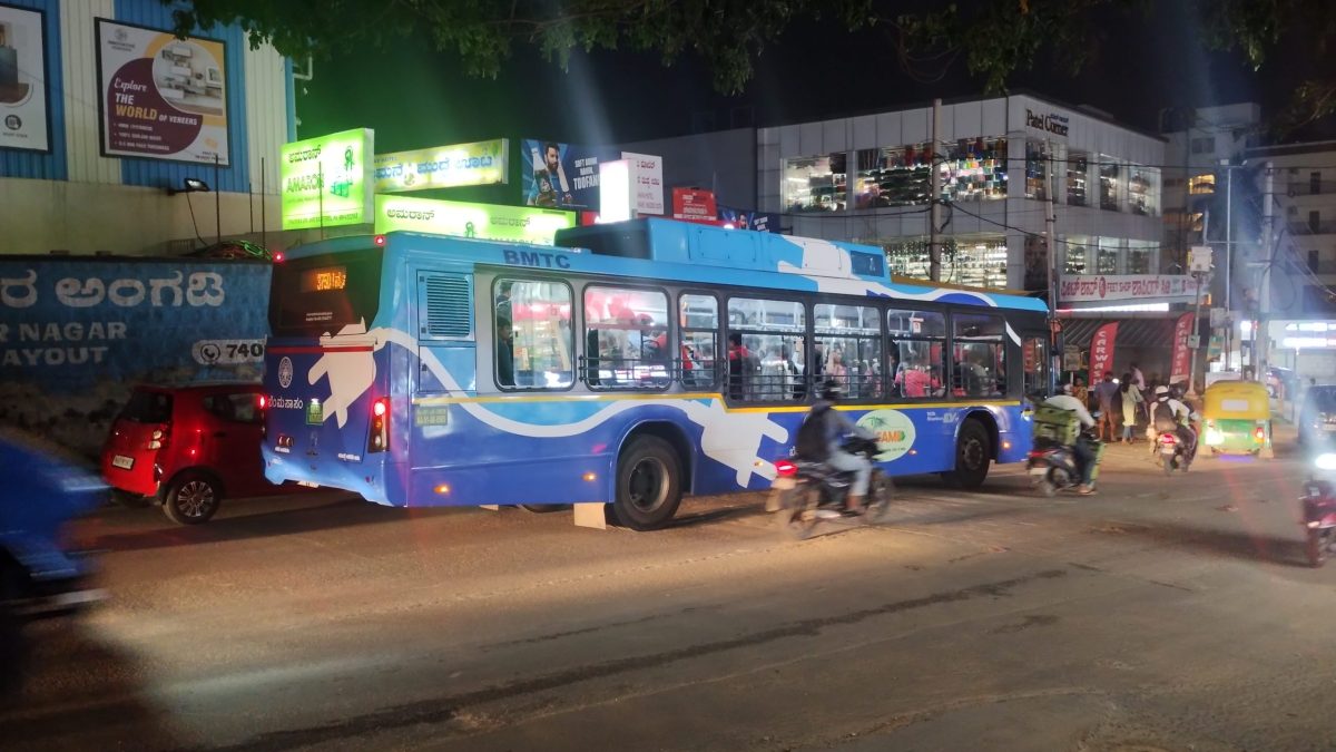 A blue BMTC city bus on a street in Bengaluru at night