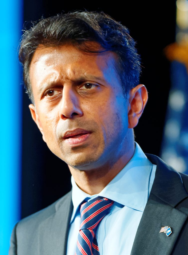 Bobby Jindal in a suit speaking at a lectern