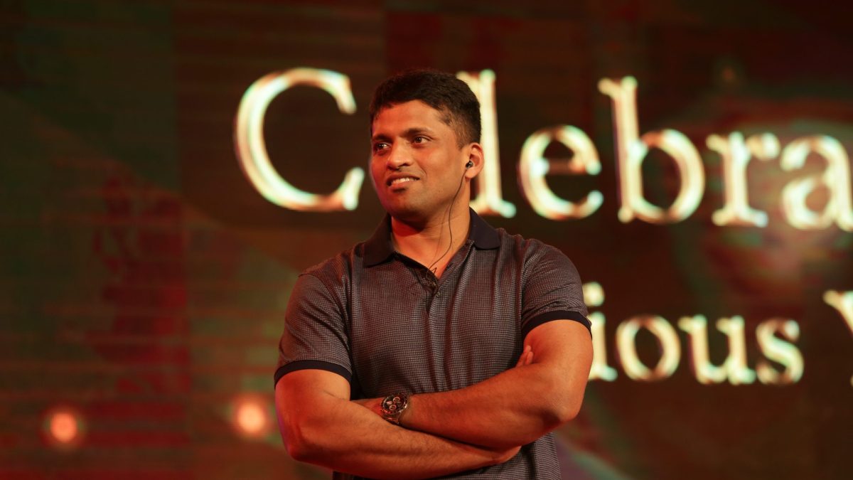 Byju Raveendran in a dark polo shirt standing with arms crossed on a stage
