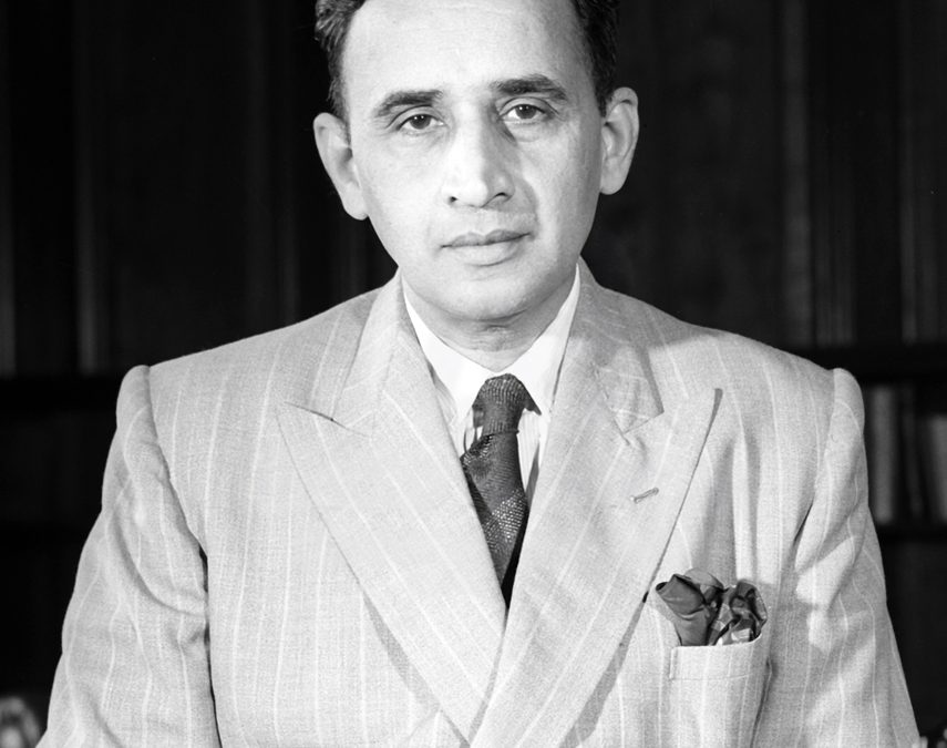 A black-and-white photograph of C. D. Deshmukh seated, in a light suit