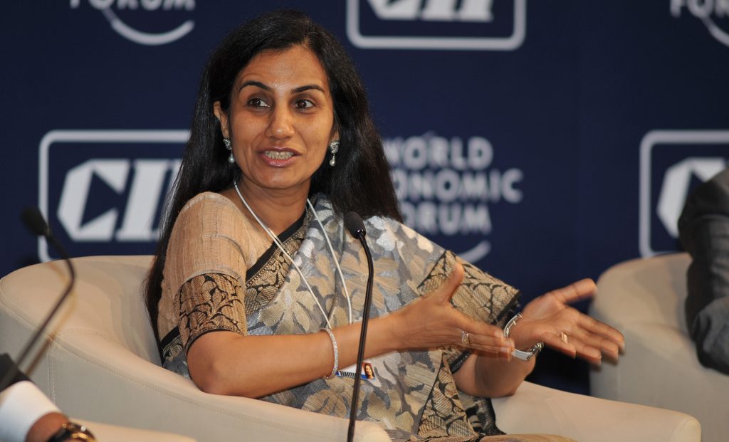 Chanda Kochhar in a sari seated on stage, gesturing as she speaks