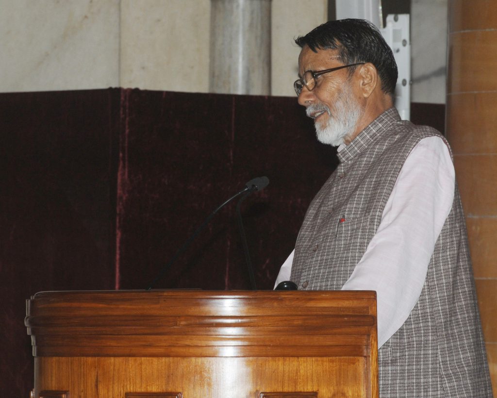 Chandi Prasad Bhatt with a white beard and checked waistcoat speaking at a wooden lectern
