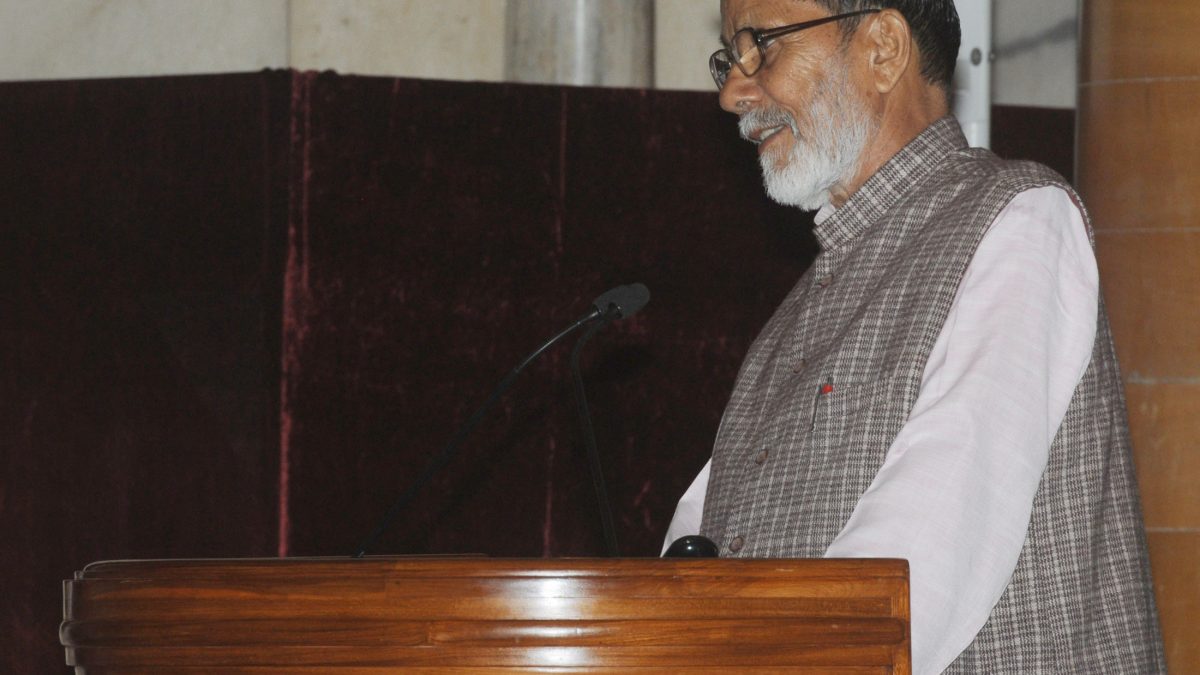 Chandi Prasad Bhatt with a white beard and checked waistcoat speaking at a wooden lectern