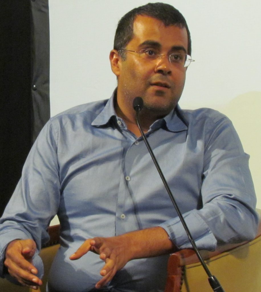 Chetan Bhagat in a dark shirt speaking at a book event