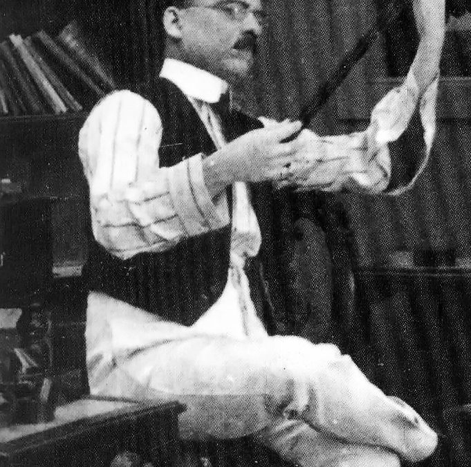 Dadasaheb Phalke seated on a chair examining a strip of film