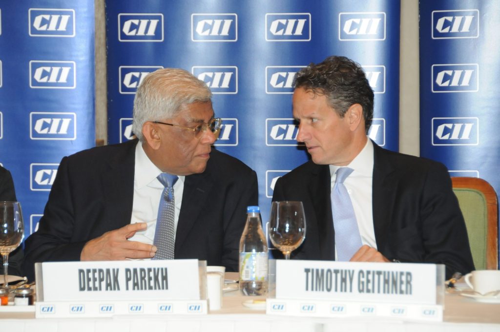 Deepak Parekh seated at a meeting table beside Timothy Geithner