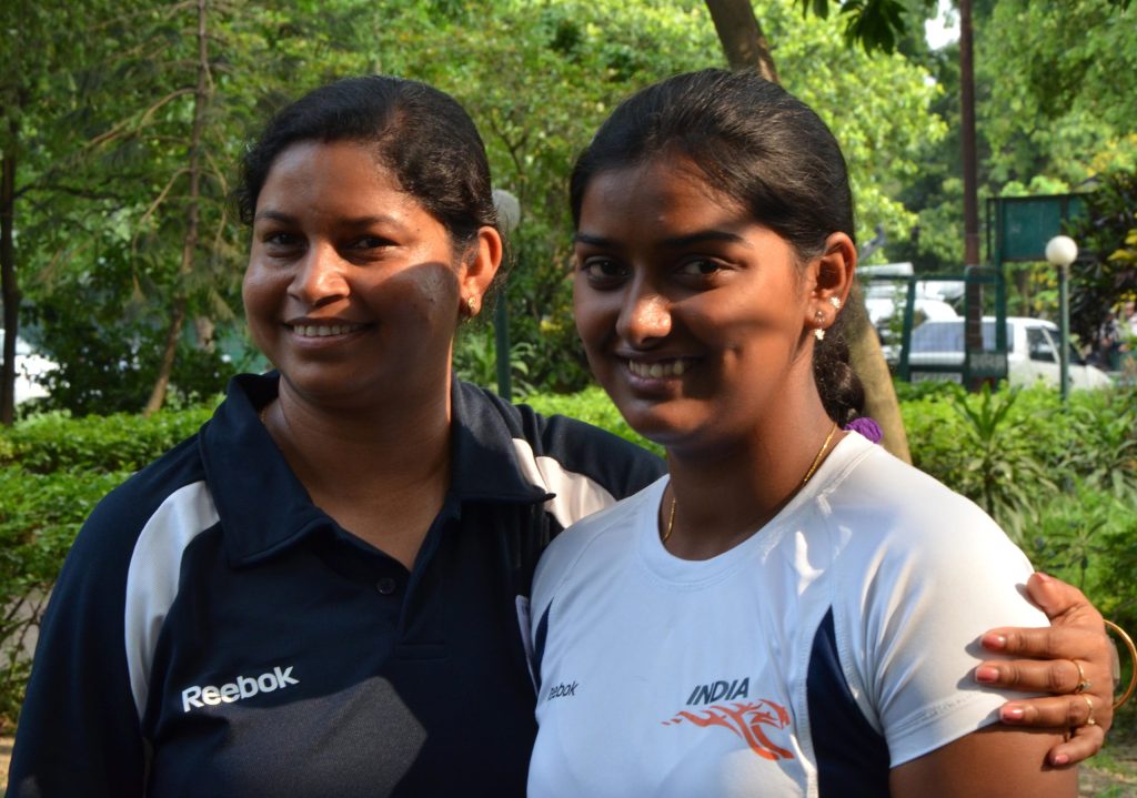 Deepika Kumari smiling in an India jersey beside her coach Purnima Mahato