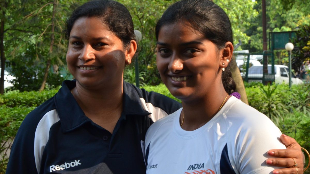 Deepika Kumari smiling in an India jersey beside her coach Purnima Mahato