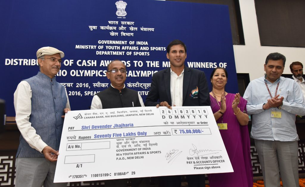 Devendra Jhajharia standing beside a cheque for Rs 75 lakh at a ceremony for Rio medal winners