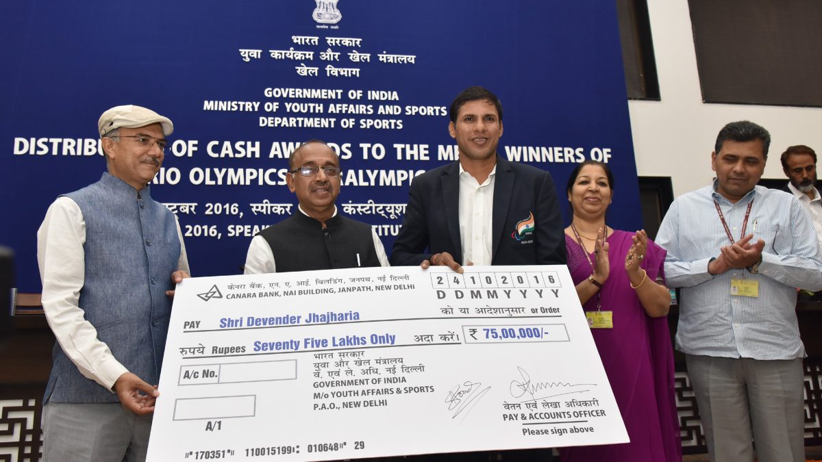 Devendra Jhajharia standing beside a cheque for Rs 75 lakh at a ceremony for Rio medal winners