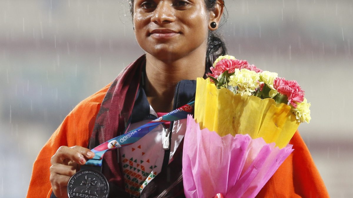 Dutee Chand holding a medal and a bouquet