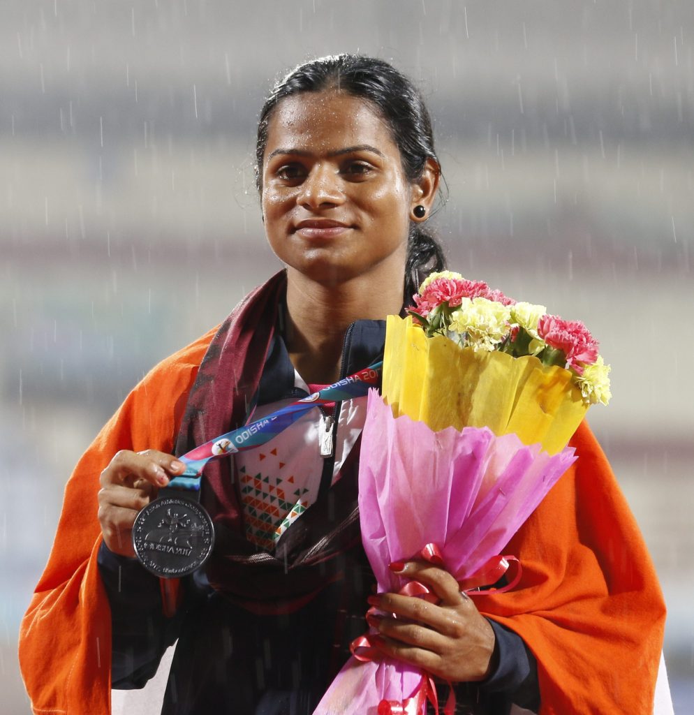 Dutee Chand holding a medal and a bouquet